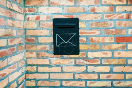 Téléchargez les photos : Vieille boîte aux lettres noire ou boîte aux lettres sur un mur de briques, espace de copie inclus - en image libre de droit