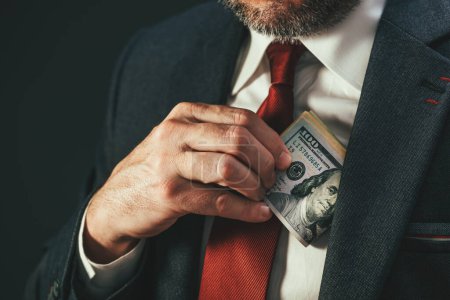 Photo for Politics and bribery, corrupted politician putting money in his suit pocket, selective focus - Royalty Free Image