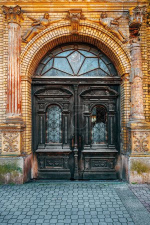 Photo for Old wooden doorway with broken glass and worn wrought iron decoration, vertical image - Royalty Free Image