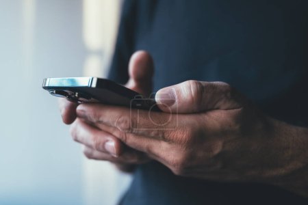 Téléchargez les photos : Homme utilisant un smartphone pour taper un message texte, mise au point sélective - en image libre de droit