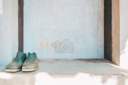 Foto de Old farming rubber boots in front of the door, selective focus - Imagen libre de derechos