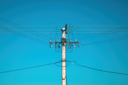 Foto de Poste de electricidad con cables aéreos y farola contra el cielo azul - Imagen libre de derechos