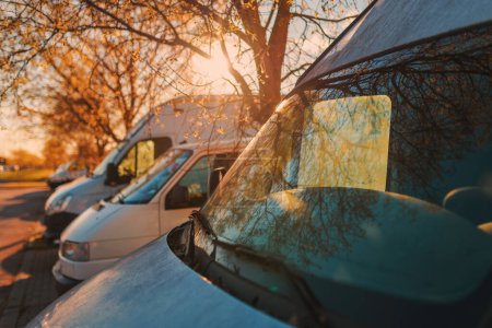 Téléchargez les photos : Transport et logistique, véhicules utilitaires blancs sur un parking au coucher du soleil d'été, accent sélectif - en image libre de droit