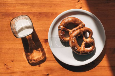Téléchargez les photos : Deux bretzels sur une assiette et un verre de yaourt sur la table le matin est le petit déjeuner parfait, vue sur le dessus - en image libre de droit