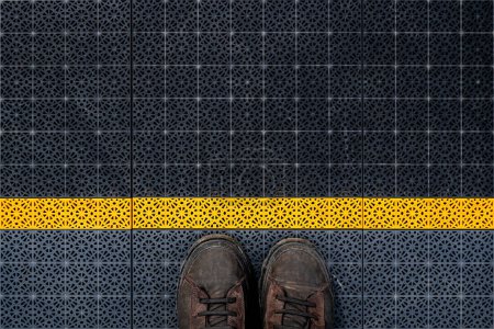 Waiting line, male boots on non slip plastic flooring with triangular pattern from above, copy space included