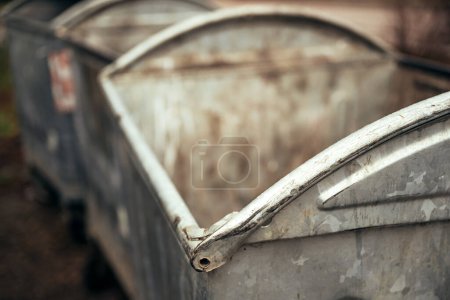 Worn old metallic garbage dumpster container or dust bins at the street, selective focus