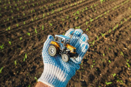 Landwirt mit Kunststoff-Druckguss-Traktor landwirtschaftliches Fahrzeug im Feld, selektiver Fokus