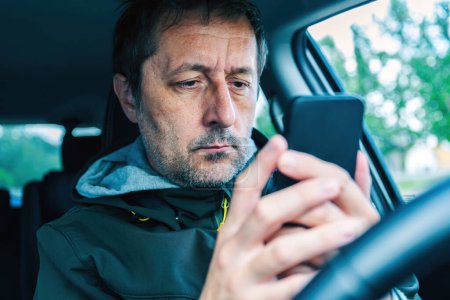 Téléchargez les photos : Conducteur masculin utilisant un smartphone en voiture, mise au point sélective - en image libre de droit