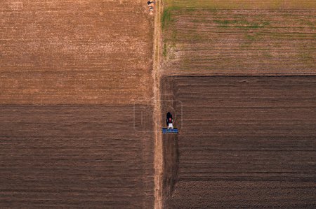 Photo for Tractor with tiller equipment plowing farmland soil, aerial shot top down - Royalty Free Image