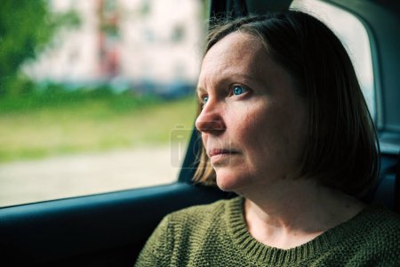 Frau denkt und übt Achtsamkeit während des Pendelns zur Arbeit auf dem Rücksitz eines Taxifahrzeugs, selektiver Fokus