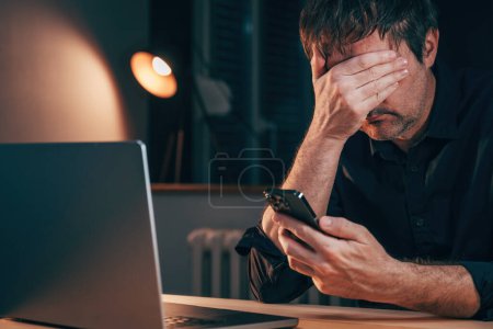 Téléchargez les photos : Sad unhappy disappointed freelancer reading worrying text message on smartphone, selective focus - en image libre de droit