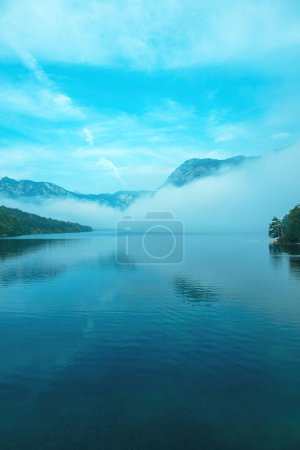 Téléchargez les photos : Brouillard matinal et brouillard se levant de la surface du lac Bohinj au lever du soleil d'été, image verticale - en image libre de droit