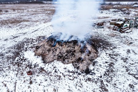 Téléchargez les photos : Brûlage de tas de fumier à la ferme, pollution et contamination de l'air, tir aérien depuis le point de vue du drone, vue en angle élevé - en image libre de droit