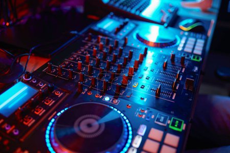 Closeup on dj turntable in neon light, sound recording equipment knobs, music mixer