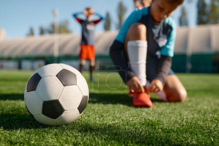 Téléchargez les photos : Ballon de football sur l'herbe foyer sélectif. Entraînement d'équipe de football pour enfants avec peu de profondeur de terrain - en image libre de droit