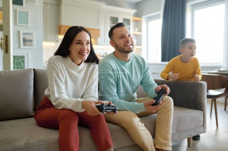 Photo for Overjoyed family with kid. Happy son watching while mother and father playing video game - Royalty Free Image