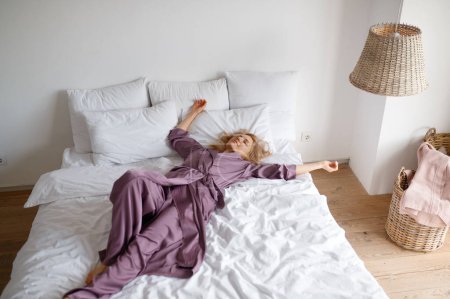 Téléchargez les photos : Attractive woman relaxing on bed. Pretty carefree girl posing for camera - en image libre de droit