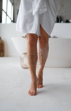 Foto de Vista de sección baja de pies espumosos húmedos femeninos descalzos pisando el piso del baño. Rutina de higiene - Imagen libre de derechos