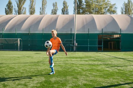 Foto de Niños jugando al fútbol, un joven futbolista con uniforme golpeando pelota. Escuela estadio al aire libre - Imagen libre de derechos