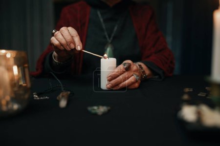 Téléchargez les photos : Closeup hands of gypsy fortune teller lights candle for divination session. Future reading concept - en image libre de droit