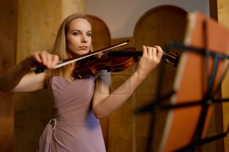 Foto de Lonely young female violinist playing fiddle at studio. Full-length portrait of musician - Imagen libre de derechos