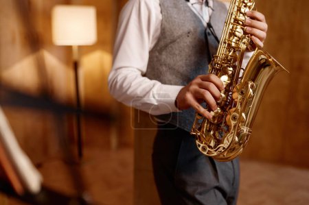 Téléchargez les photos : Cropped shot of young musician standing and playing saxophone. Musical jazz or blues performance - en image libre de droit