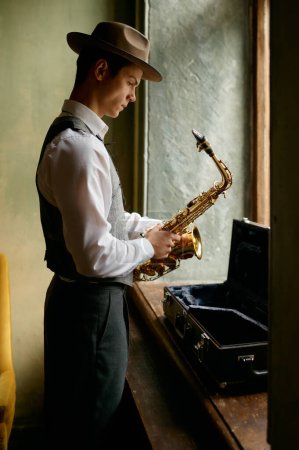 Téléchargez les photos : Young musician putting saxophone into case after practicing on music lesson side view - en image libre de droit