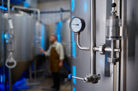 Téléchargez les photos : Gauge valve to measure and control pressure during brewing process at craft beer manufactory. Background with selective focus - en image libre de droit