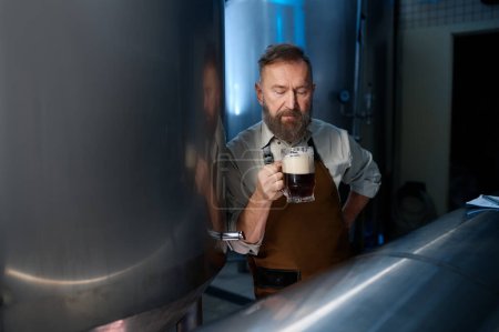 Photo for Mature brewery factory owner examining quality of craft beer. Adult man inspector working on alcohol manufacturing factory checking ale fermentation - Royalty Free Image