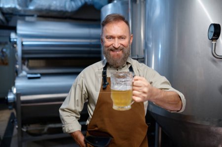 Téléchargez les photos : Freshly made craft beer in glass closeup. Brewery worker holding mug with fresh ale. Selective focus. Brewery concept - en image libre de droit