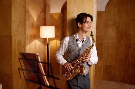 Photo for Jazz musician playing saxophone and leaning against art studio wall. Training before performance - Royalty Free Image