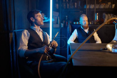 Photo for Stylish guys smoking hookah in bar while talking. Concept of having good time and nice conversation - Royalty Free Image