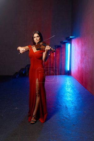 Téléchargez les photos : Jolie violoniste. Joueuse de violon en solo sur fond intérieur industriel loft - en image libre de droit