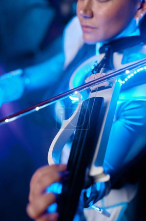 Photo for Portrait of young fashion violinist playing electronic music on violin. Neon light atmospheric shot, selective focus - Royalty Free Image