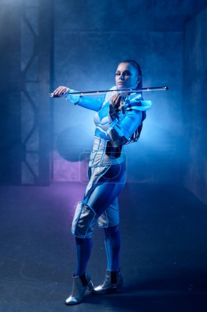 Téléchargez les photos : Violoniste femme jouant du violon électrique futuriste avec un accent sélectif sur ses doigts sur les cordes. Portrait avec fumée et éclairage au néon - en image libre de droit
