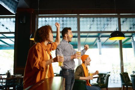 Photo for Friends fans watch sport tv online match in pub and cheering together. Young people with raised hands drinking beer and supporting favorite team on championship - Royalty Free Image