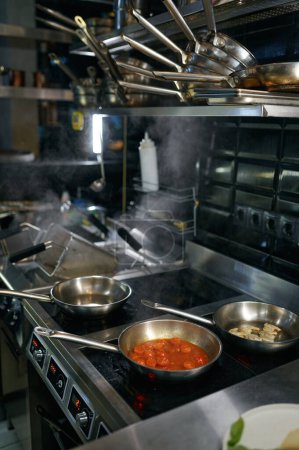 Téléchargez les photos : Traditional vegetarian pasta preparation at modern kitchen gas stove in wok pan. Creative cooking master class - en image libre de droit
