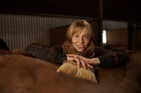 Foto de Headshot portrait of young smiling horsewoman behind horseback of her well-groomed purebred stallion - Imagen libre de derechos
