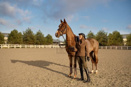 Téléchargez les photos : A horse trainer with her stallion outdoors spending time at countryside farm. Horsewoman on rancho - en image libre de droit