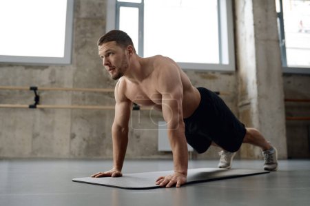 Foto de Young athletic man doing push-ups physical workout in gym. Sports training for health and strong body - Imagen libre de derechos