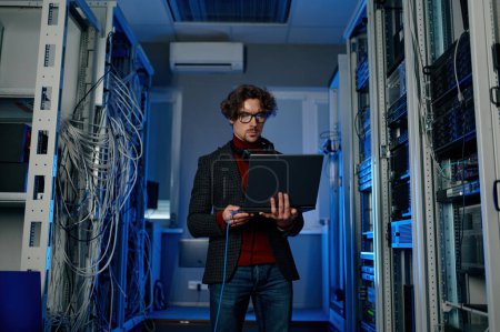 Photo for Man IT specialist with laptop working on datacenter software update in server room. Information technology concept - Royalty Free Image
