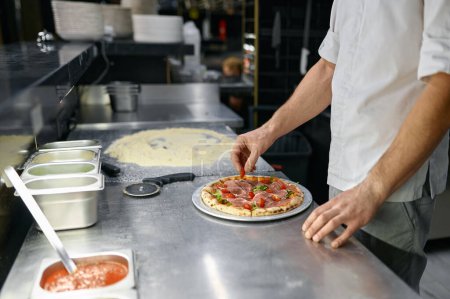 Photo for Pizzaiolo making pizza at kitchen with closeup focus on hand. Italian pastry preparation for delicious lunch or dinner - Royalty Free Image