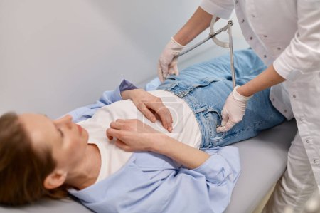 Foto de Médico ginecólogo que mide el volumen de cadera del paciente femenino durante el chequeo en el centro médico prenatal - Imagen libre de derechos