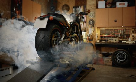 Téléchargez les photos : Moto dans des nuages de fumée debout dans un garage pour motards ou motards. Diagnostic de moto, concept d'entretien et de réparation - en image libre de droit