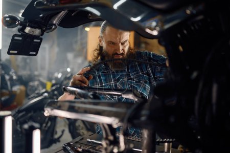 Photo for Man biker fixing motocycle engine. Mechanic working at garage workstation. Motorbike repair service concept - Royalty Free Image