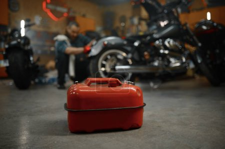 Foto de Enfoque selectivo en bidón de combustible en garaje para motocicletas. Motociclista maduro reparación de la motocicleta sobre fondo borroso - Imagen libre de derechos