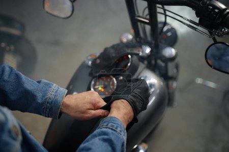 Photo for Closeup view on biker hand wearing leather gloves over motorcycle gas tank. Motorbike garage concept - Royalty Free Image