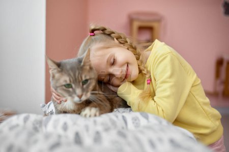 Foto de Feliz chica sonriente acariciando gato esponjoso divertirse en refugio de animales. Alegre niño abrazando grande peludo gatito - Imagen libre de derechos