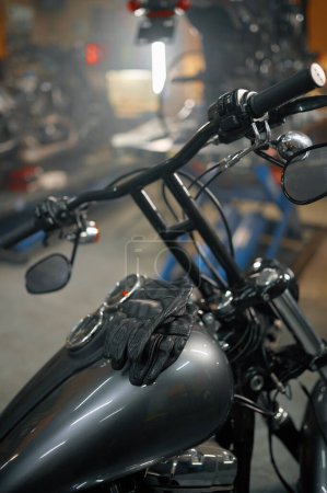 Foto de Concepto de garaje para motocicletas. Vista detallada de los guantes de ciclista de cuero en el tanque de gasolina de moto - Imagen libre de derechos