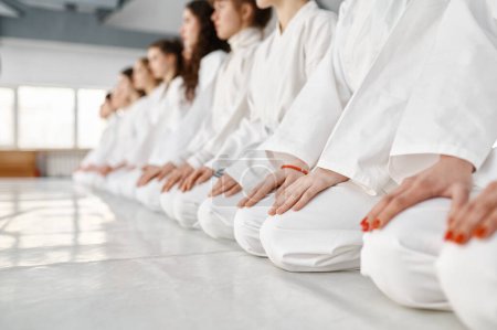 Photo for Young woman team in white martial arts uniform sitting on floor in gym. Closeup, selective focus. Japanese martial arts concept - Royalty Free Image